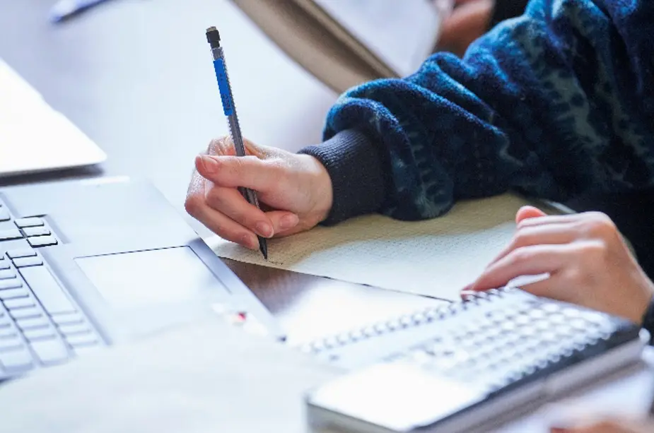 hand holding pencil writing on graph paper 
