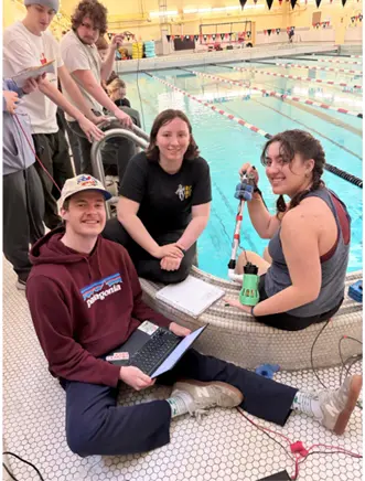 A group of people conducting a scientific experiment or data collection by an indoor swimming pool.